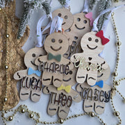 Wooden gingerbread men ornaments with names against a snowy tree background