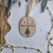 Wooden ornament with 'Bodhi's First Christmas 2023' text, surrounded by festive decorations on a white background.