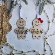 Two wooden gingerbread ornaments with names 'Charlie' and 'Olivia' hanging on a Christmas tree.