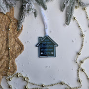 Decorative house-shaped ornament with text on a Christmas tree background